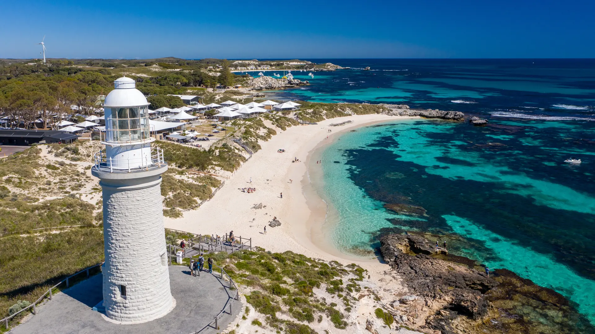 Bathurst Lighthouse above a white beach and turquoise bay on Rottnest Island, from the Hillarys ferry transfer listing