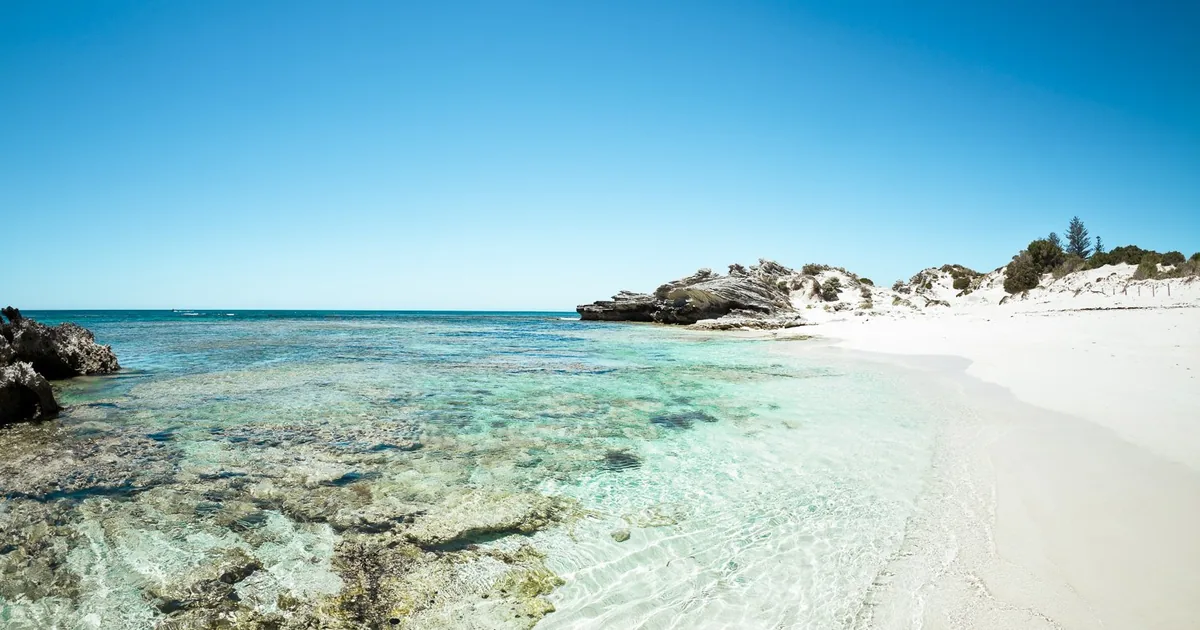 Clear shallow water over pale sand and limestone reef at a quiet beach on Rottnest Island